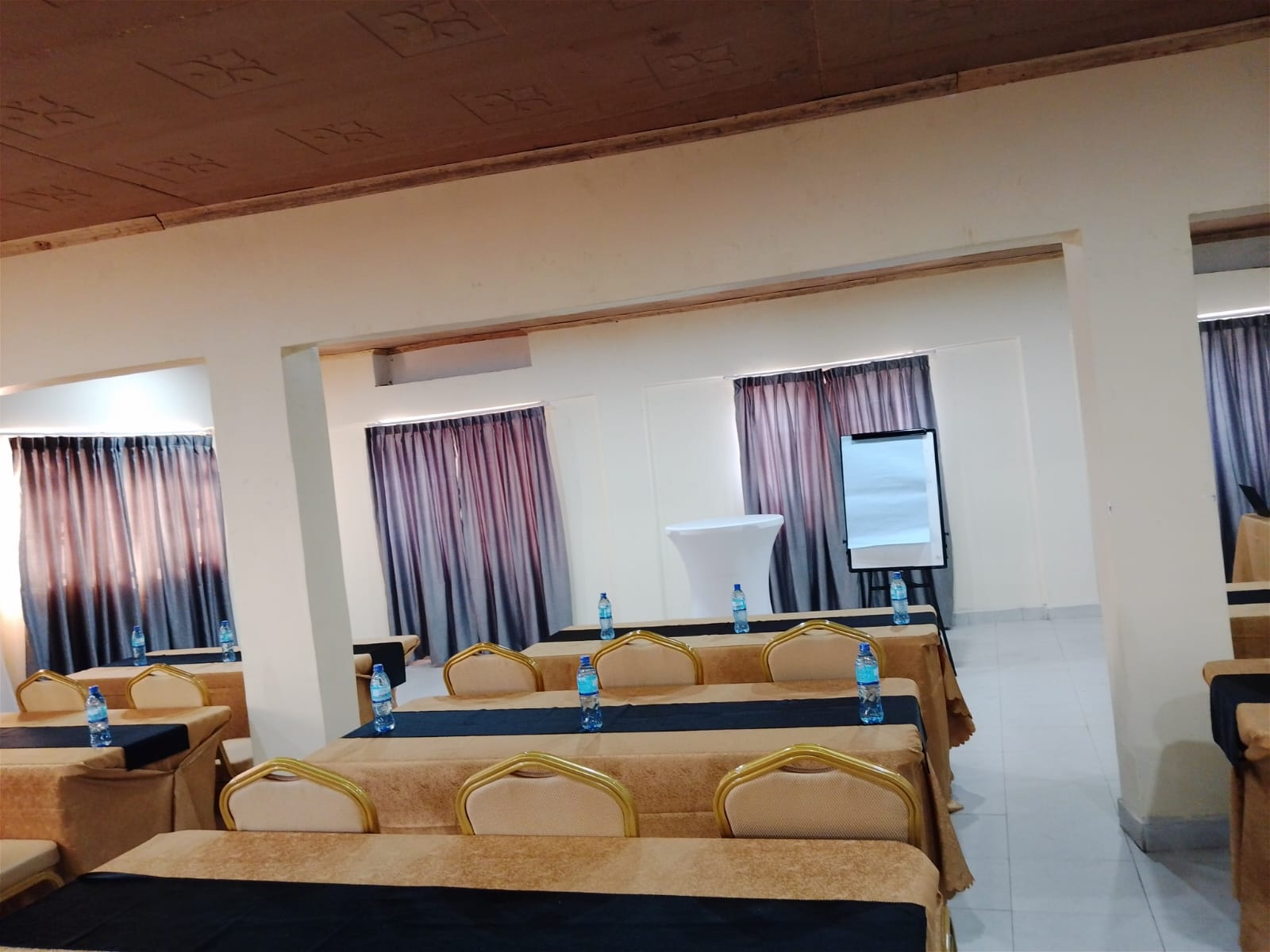 Conference tables with water, notebooks and gold-trim seating at The Ellena Hotel